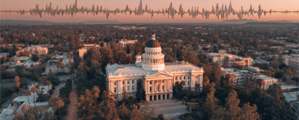 Aerial view of the California State Capitol building at sunset with a soundwave graphic superimposed over the sky.